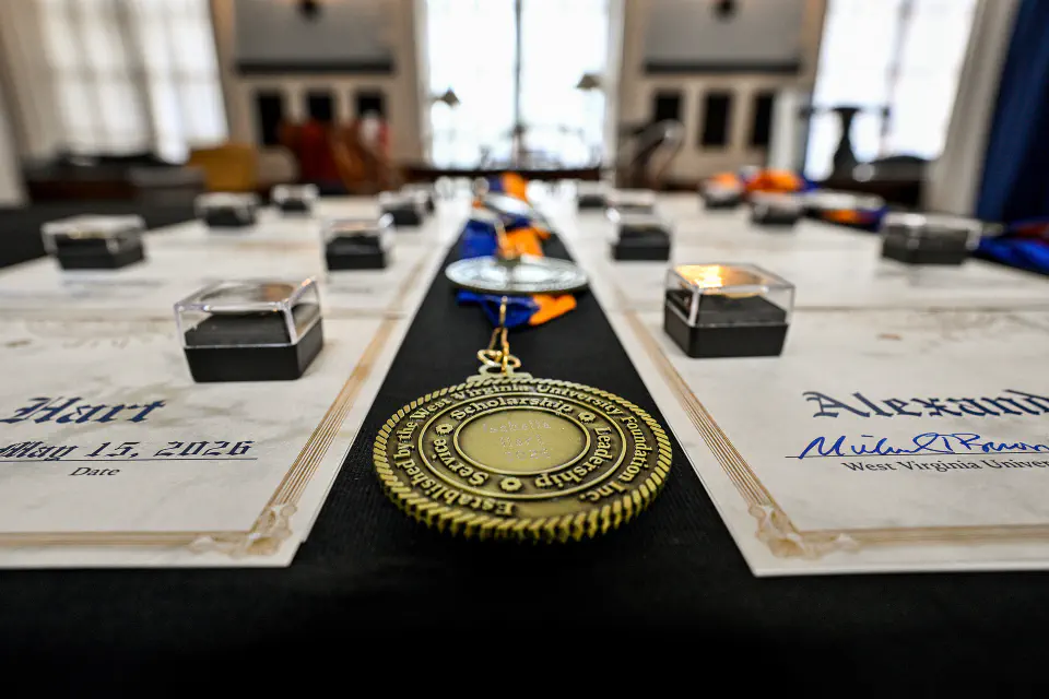 A close-up image shows awards and certificates laid out on a table, hinting at an academic or celebratory event.