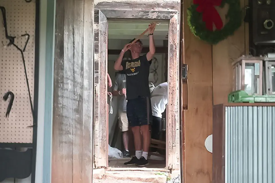 A group of young people are engaged in some sort of activity or construction work in a rustic, unfinished building.