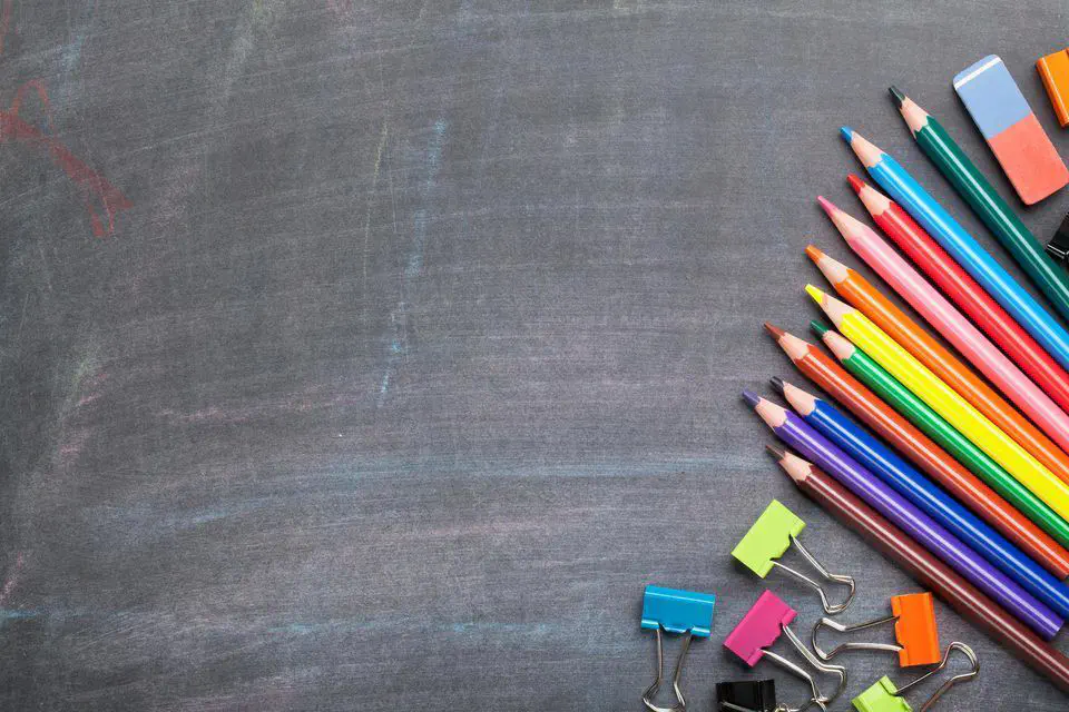 A colorful array of art supplies is neatly arranged on a chalkboard surface, evoking a sense of readiness for learning and creativity.